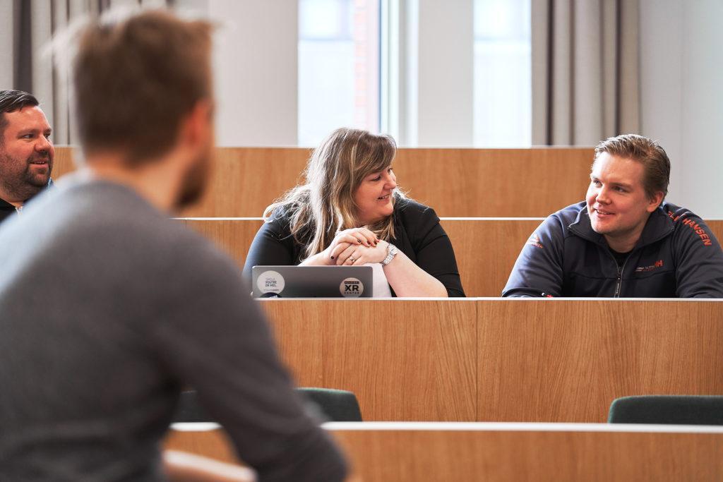 Four people sitting in a classroom having a chat with each other.