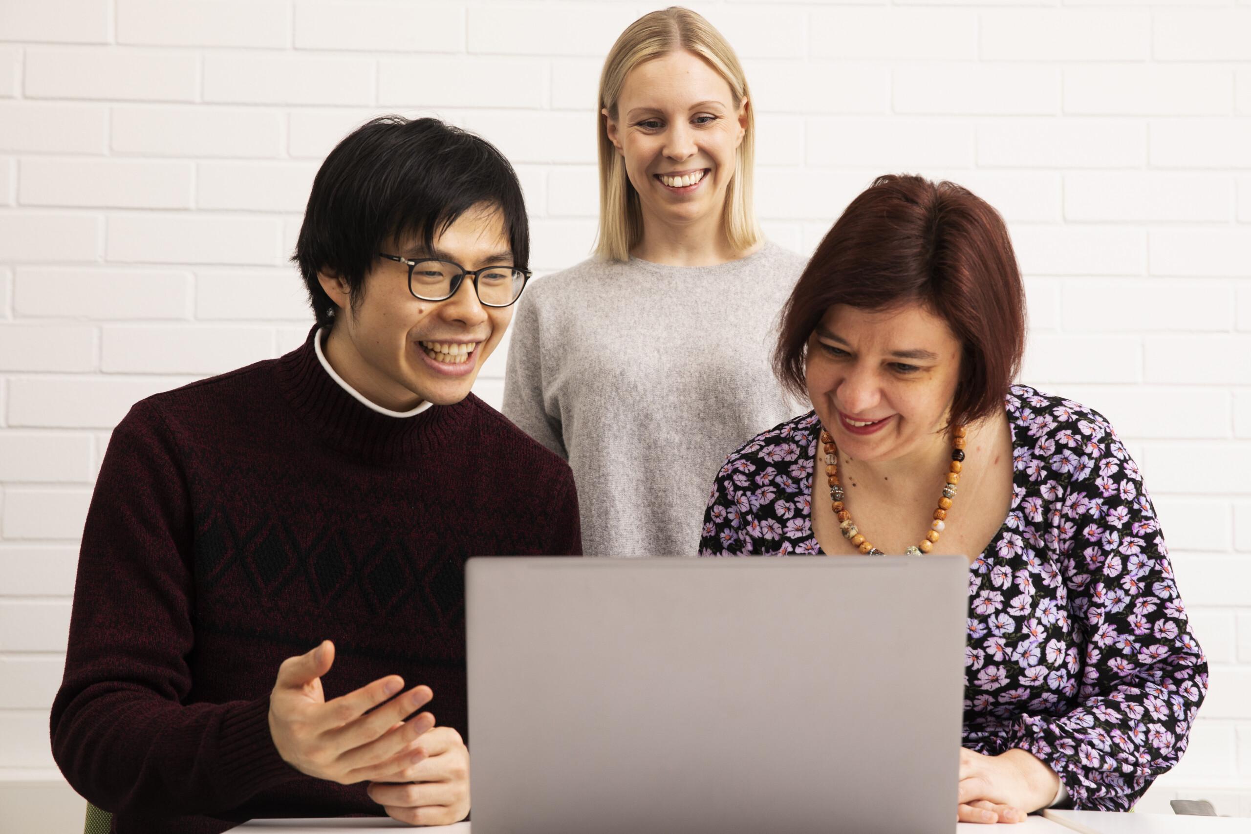 Group of people discussing and looking at a laptop.