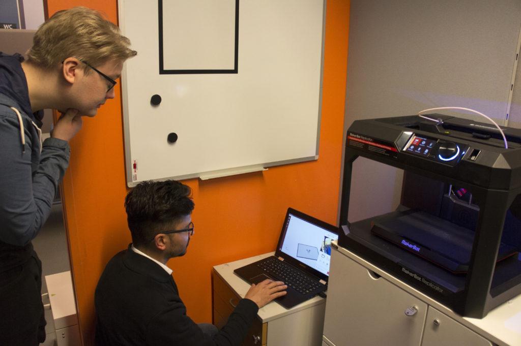 Two students watch the screen of a laptop.